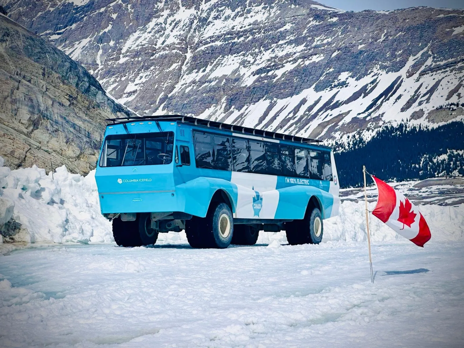 Pursuit's electric Ice Explorer on the Athabasca Glacier beside a Canadian flag